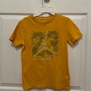 A classic T-shirt by Air Jordan. Size 10 in boys and yellow with a blue 23 on it